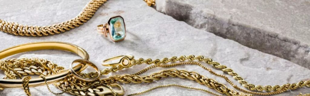 Verschiedene Schmuckstücke aus Gold, darunter Ketten, Ringe, Armbänder und ein Ring mit Edelsteinbesatz. Die Darstellung veranschaulicht den Verkauf von Schmuck in Heidelberg sowie die fachgerechte Wertermittlung und den Ankauf von Goldschmuck und Schmuckwerten.